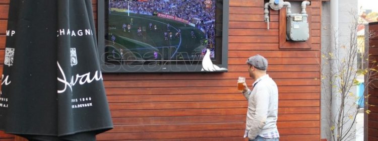 Man watching TV drinking a beer in a beer garden